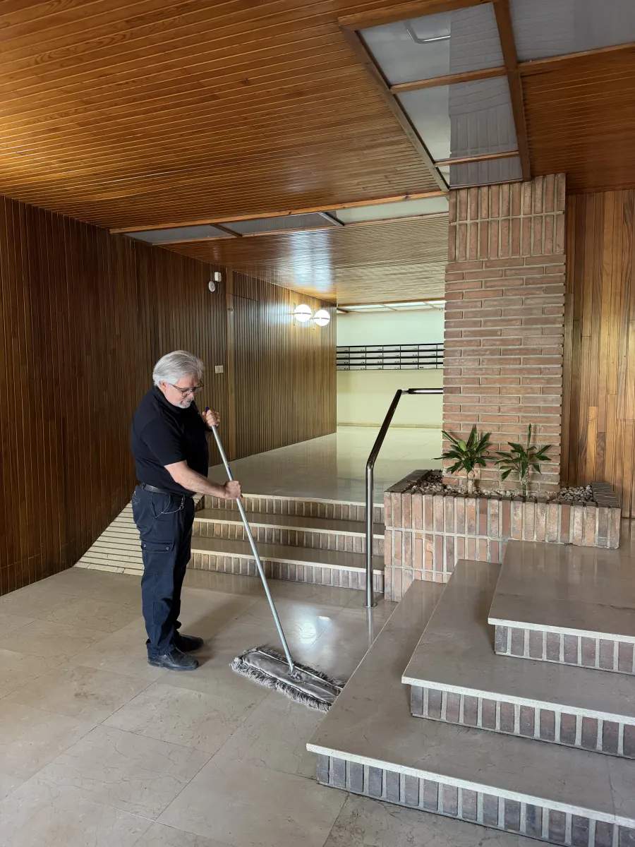 Operario limpiando el portal de la finca con la mopa