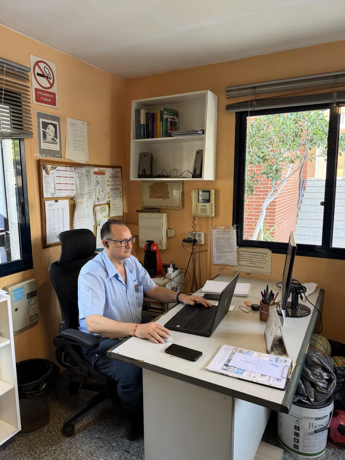 Conserje trabajando con el ordenador en la oficina de la portería