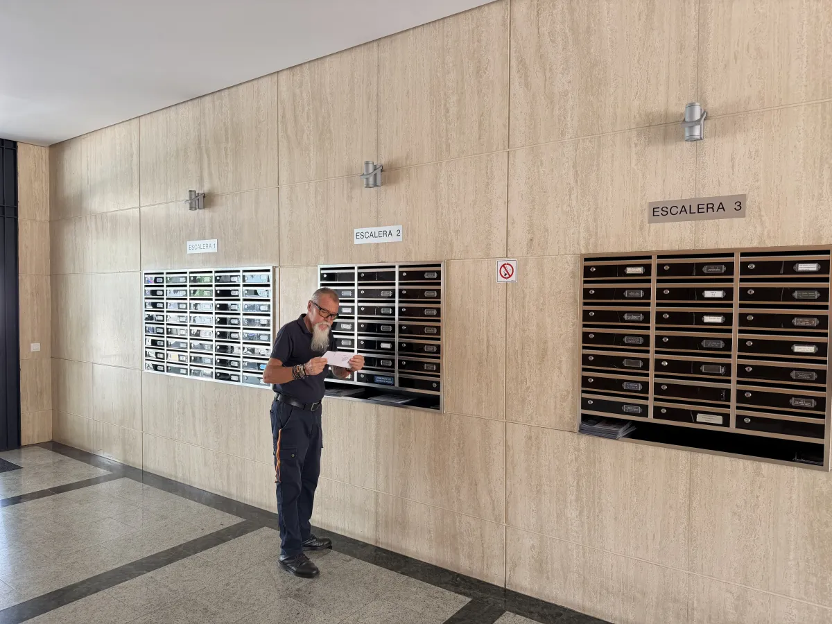 Conserje repartiendo la correspondencia en la buzonería del portal