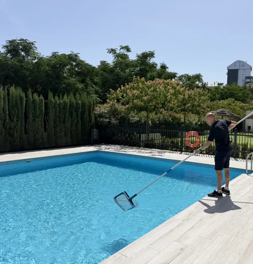 Operario limpiando la piscina de la comunidad