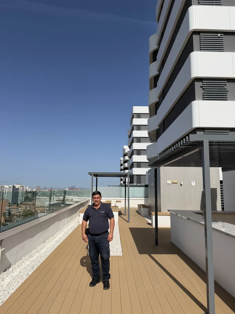 Empleado uniformado en la azotea de una finca, con el skyline de Valencia al fondo