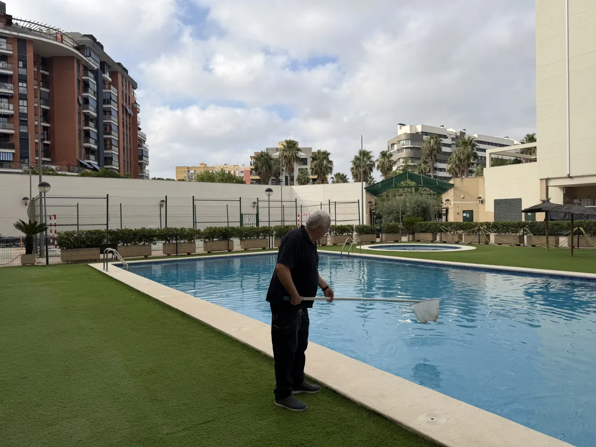 Operario limpiando la piscina de la comunidad